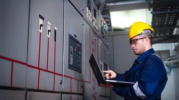 Electrical engineer check the operation of the main electrical control panels system on laptop photo