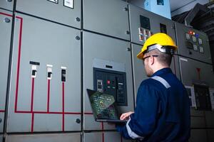 Electrical engineer check the operation of the main electrical control panels system on laptop photo
