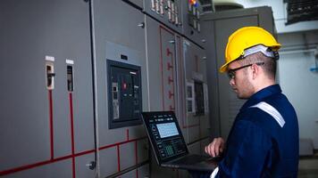Electrical engineer check the operation of the main electrical control panels system on laptop photo
