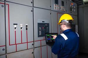 Electrical engineer check the operation of the main electrical control panels system on laptop photo
