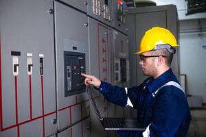 Electrical engineer check the operation of the main electrical control panels system on laptop photo