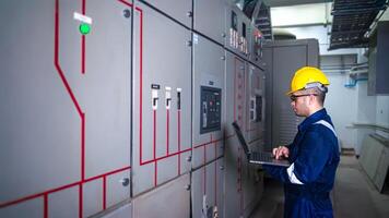 Electrical engineer check the operation of the main electrical control panels system on laptop photo
