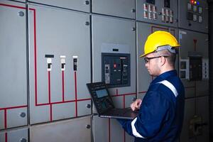 Electrical engineer check the operation of the main electrical control panels system on laptop photo