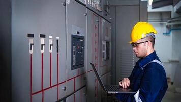 Electrical engineer check the operation of the main electrical control panels system on laptop photo