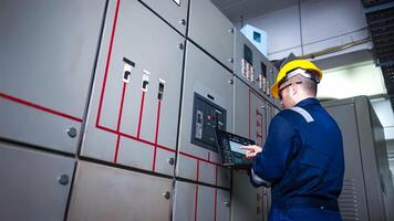 Electrical engineer check the operation of the main electrical control panels system on laptop photo