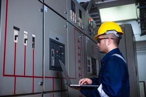 Electrical engineer check the operation of the main electrical control panels system on laptop photo