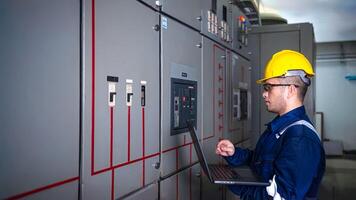 Electrical engineer check the operation of the main electrical control panels system on laptop photo