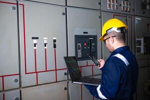 Electrical engineer check the operation of the main electrical control panels system on laptop photo