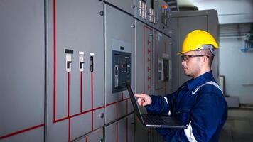 Electrical engineer check the operation of the main electrical control panels system on laptop photo