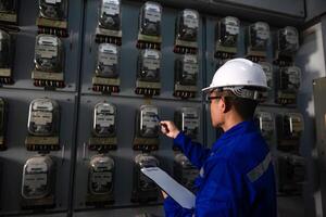 Electrical maintenance engineer is checking .Electricity meter, main distribution board and write down value of electricity on a clipboard photo