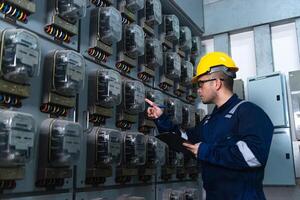 Electrical maintenance engineer is checking Electricity meter, main distribution board and write down value of electricity on a clipboard photo