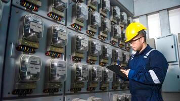 eléctrico mantenimiento ingeniero es comprobación .electricidad metro, principal distribución tablero y escribir abajo valor de electricidad en un portapapeles foto