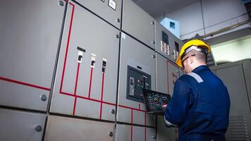 Electrical engineer check the operation of the main electrical control panels system on laptop photo