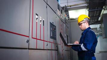 Electrical engineer check the operation of the main electrical control panels system on laptop photo