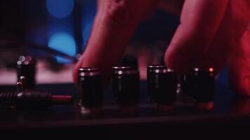Close-up of the hands of a musician carefully adjusting knobs on a mixing console during the music recording session in a studio in a dark light video