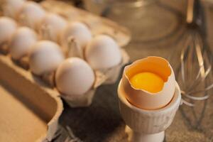 large broken chicken egg in a special container on the background of a box with eggs photo