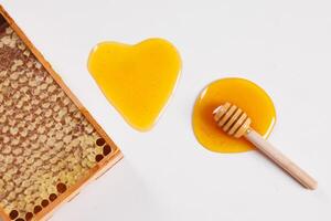 honey in the shape of a heart and bee honeycomb on a white background top view photo