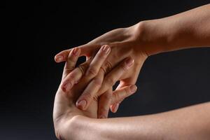 close up of female hands doing hand stretching on dark background, hand warm up concept photo