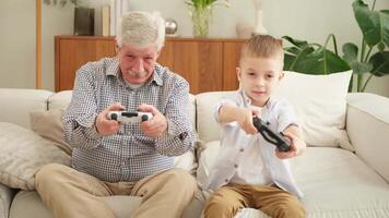 Happy family. Old senior man grandfather boy grandson playing game with joysticks at home. Smiling grandparent and child using gamepads for game. Older generation modern tech usage video