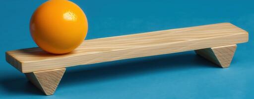Wooden plank with orange sphere on blue background represents balance and simplicity in design photo