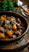 Hearty beef stew on rustic table. Home-cooked meal. Tender beef, potatoes, carrots, herbs in rich sauce photo