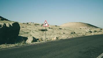 Road sign warning of a curve in the desert landscape of Mongolia during daytime video