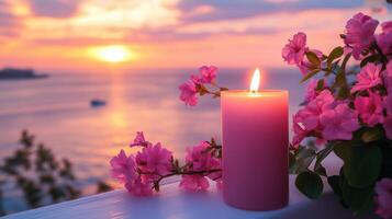 A pink candle and vibrant flowers on a balcony overlook a serene sunset photo
