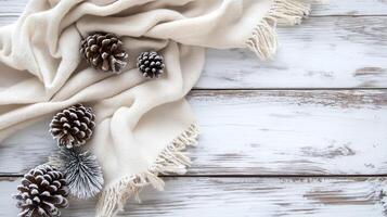 A soft cream scarf drapes alongside frosted pinecones photo