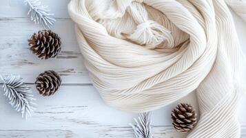 A soft cream scarf drapes alongside frosted pinecones photo