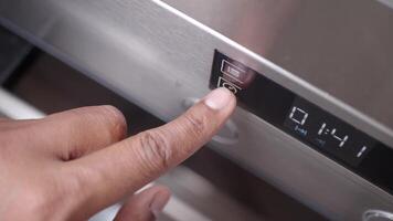 A hand is using a finger to activate the timer button on the control panel of a stainless steel oven video