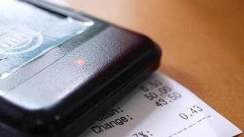A receipt is placed on a table with a cash register video