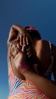 A woman is happily enjoying the sun at a beach while wearing bright and colorful attire video