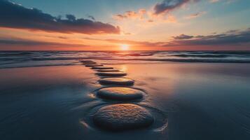 Stepping grey stones with texture forwarding in beach sand and ocean water with sunset sky photo