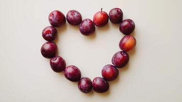 Plum fruit arranged in the shape of a heart copy space blank background photo
