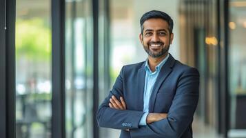 A smiling indian businessman standing in an office photo