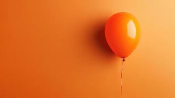 An orange balloon is hanging from a string photo