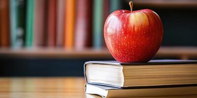An apple sits on top of a stack of books photo