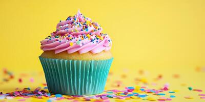A cupcake with pink frosting and sprinkles on a yellow background photo