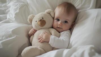 A baby is holding a teddy bear in a bed photo