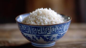 A bowl of white rice sitting on a wooden table photo