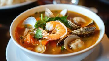 A bowl of soup with clams, shrimp and other seafood photo