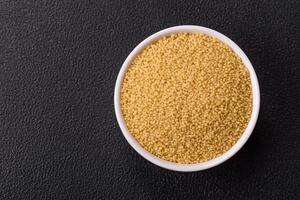 Wheat porridge couscous grains on a dark concrete background photo