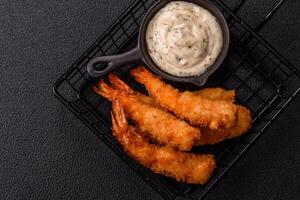 Hot crispy shrimp breaded with salt and spices with white sauce photo