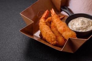 Hot crispy shrimp breaded with salt and spices with white sauce photo