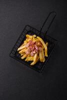 Crispy French fries with pieces of bacon, salt and spices photo