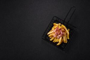Crispy French fries with pieces of bacon, salt and spices photo