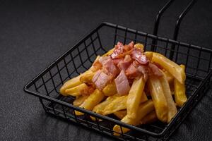 Crispy French fries with pieces of bacon, salt and spices photo