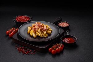 Crispy French fries with pieces of bacon, salt and spices photo