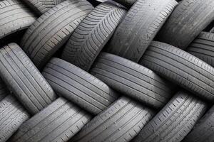 A group of used car tires stacked up are waiting to be recycled photo