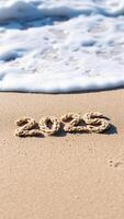 2025 written in the sand on a beach with a wave breaking in the background photo